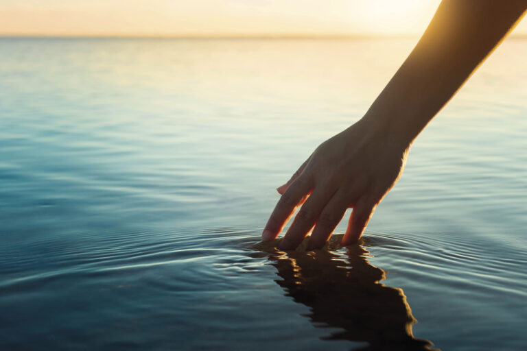 a,female,hand,touching,the,ocean,water,in,front,of